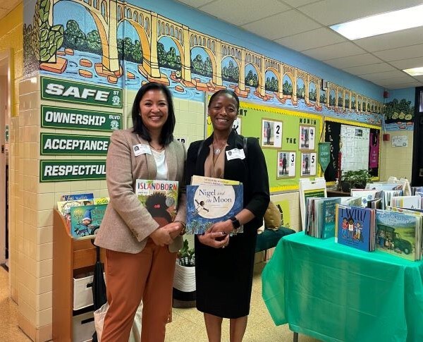 Two women stand with books